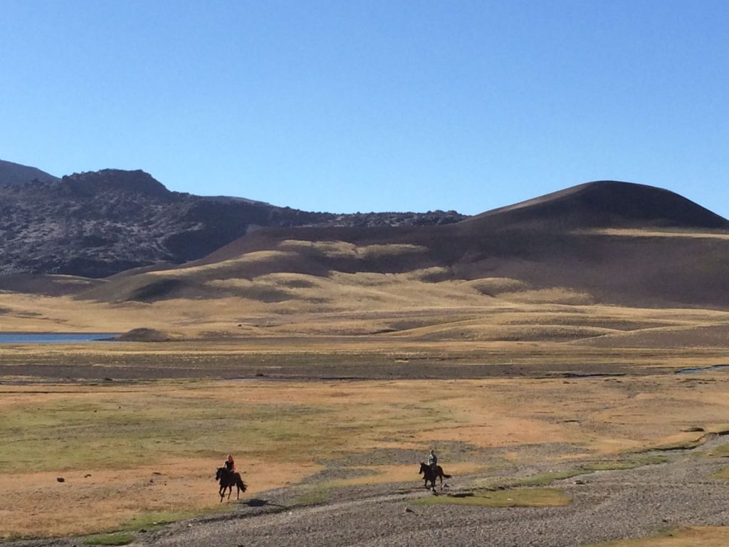 two riders galopping through the andes in chile